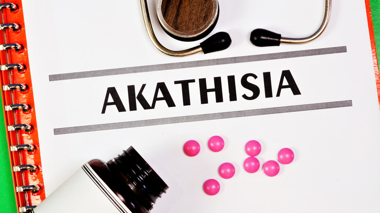 The word "Akathisia" and a bottle with pink pills spilling out