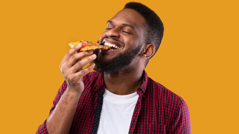 Man happily eating a slice of pizza 