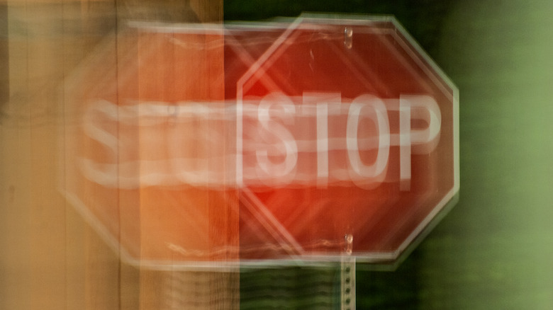 A blurred stop sign against a wooden and green background
