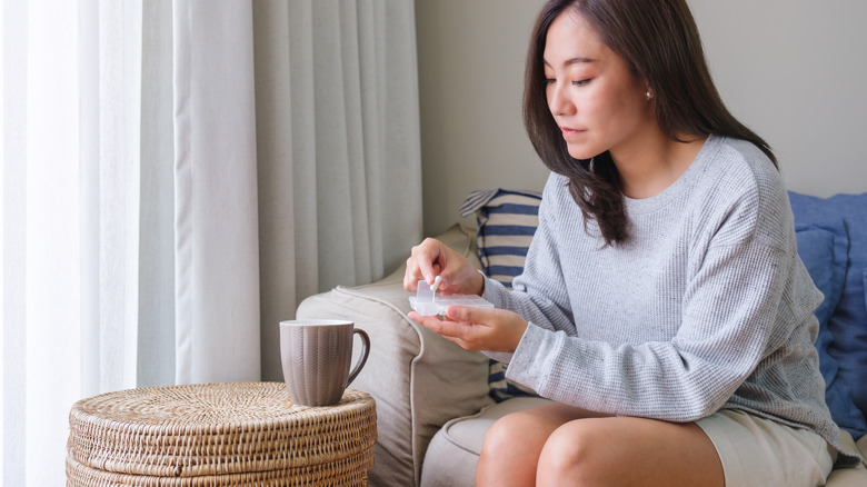 Woman getting pill from container