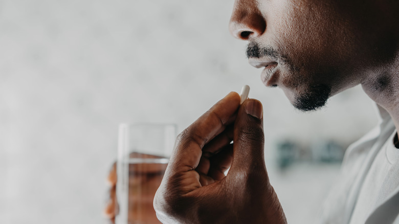 Man about to take medicine with glass of water
