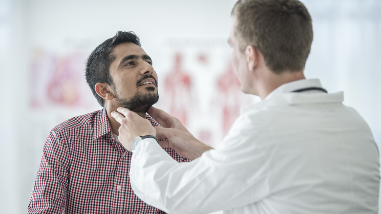 Doctor examining neck of patient