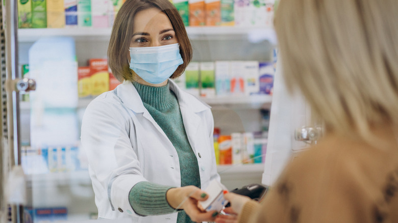 Pharmacist serving customer at drug store