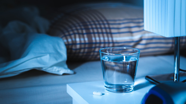 Melatonin pill on nightstand with water