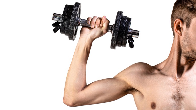 A thin young man lifting a dumbbell