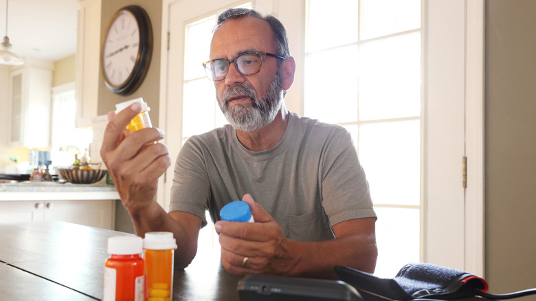 older man looking at medication bottle