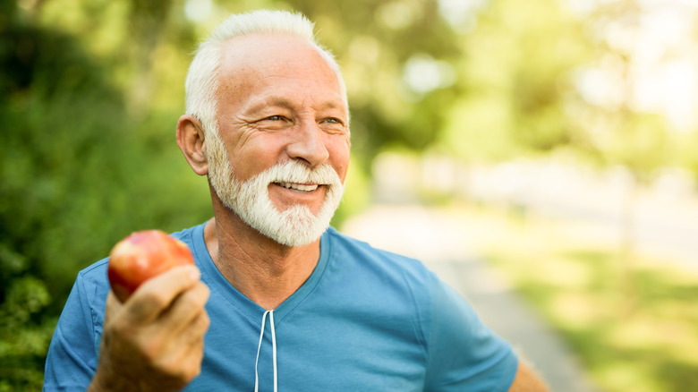 older man eating an apple outside