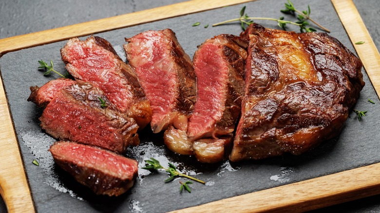 Cooked ribeye steak on a wooden board