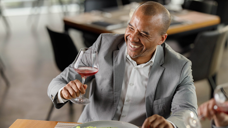 smiling man enjoying a glass of wine at a restaurant table