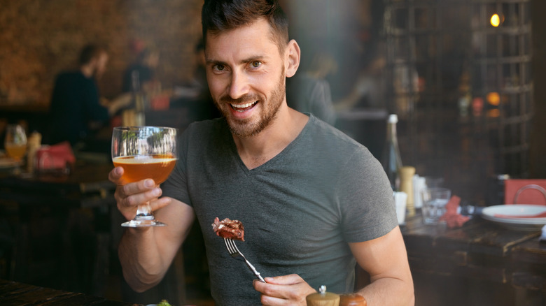 man eating steak and drinking a beer