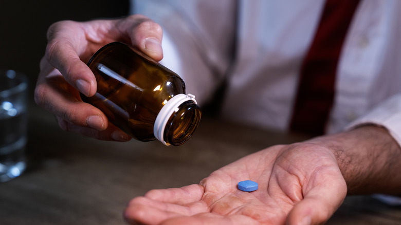 man putting Viagra tablet into hand