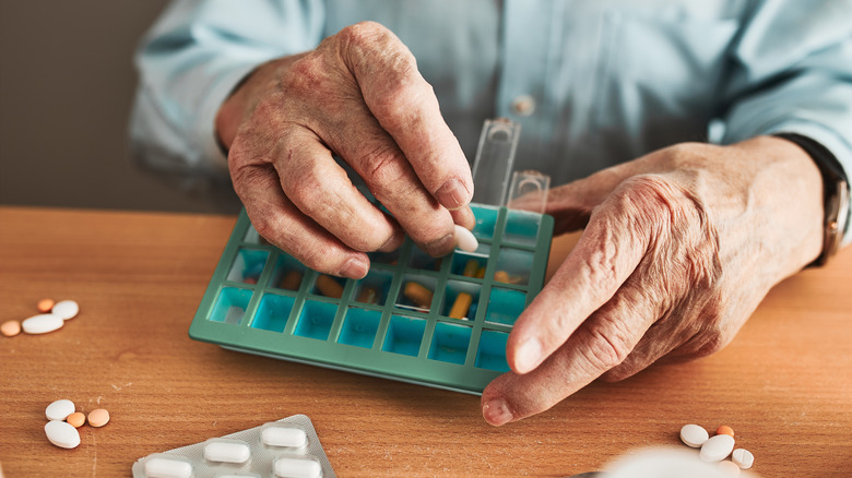 senior man organizing his medication in a dispenser