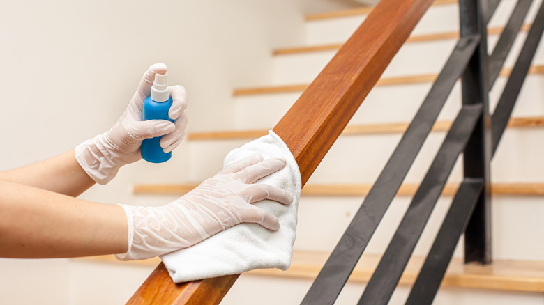 Gloved hands cleaning wooden bannister