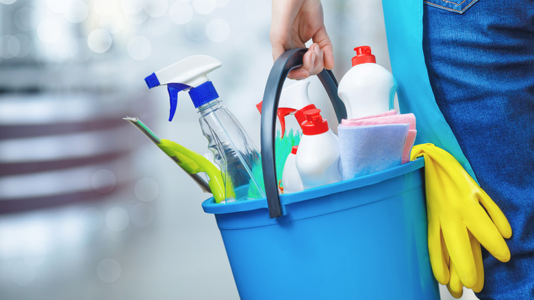 Hand holding bucket of cleaning solutions