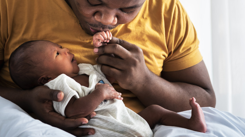 father kissing newborn baby