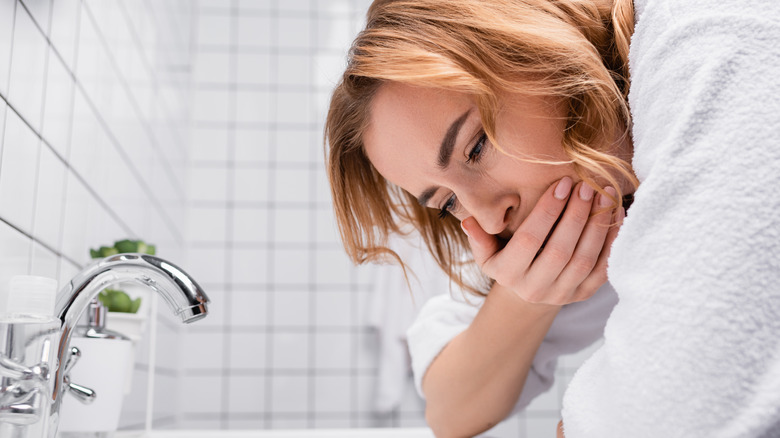 woman feeling nauseous near sink