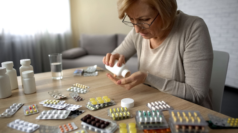 woman with a variety of pills in front of her on table