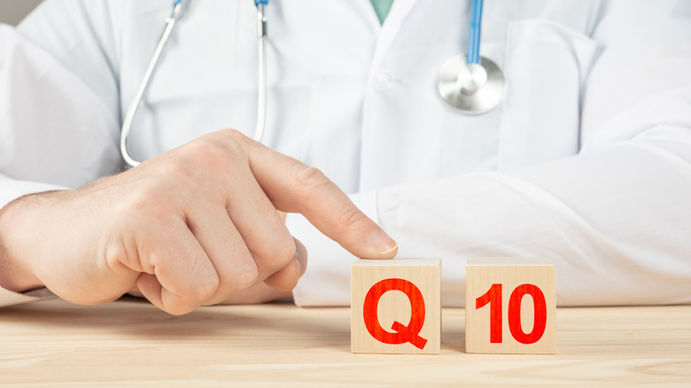 physician pointing to wooden pieces that read "Q 10"