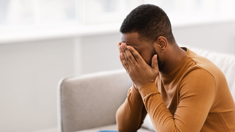 A man covers his face with his hands