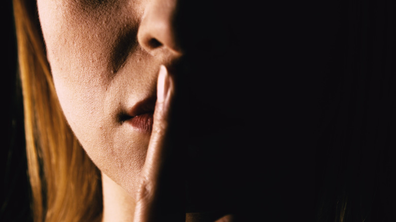 woman with finger pressed to her lips 