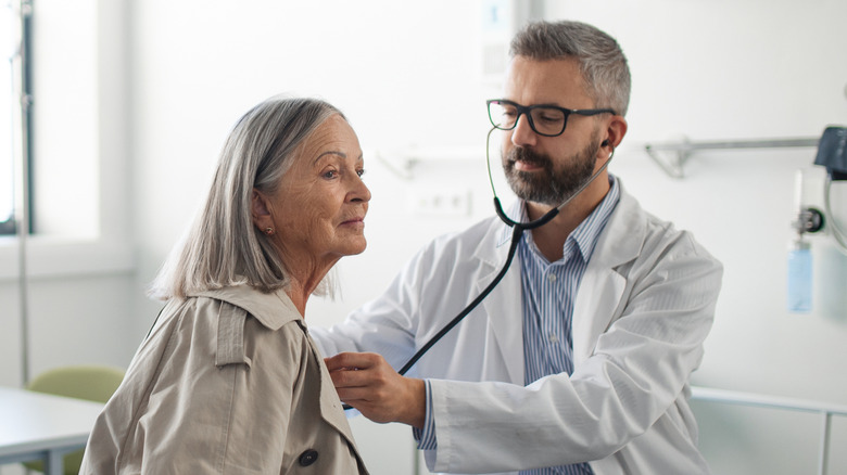 A doctor listens to a woman's heart