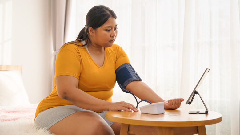 A young woman checking her blood pressure at home