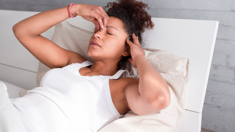 woman laying in bed looking worried and uncomfortable