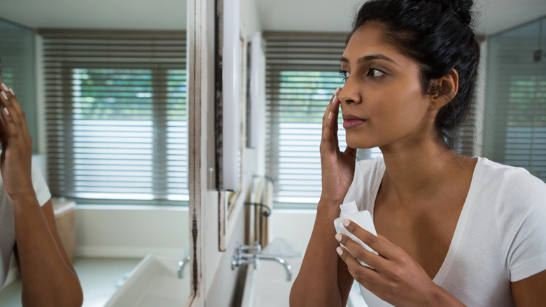 woman applying lotion to face