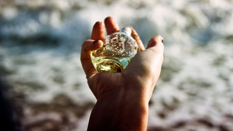 woman holding perfume near ocean