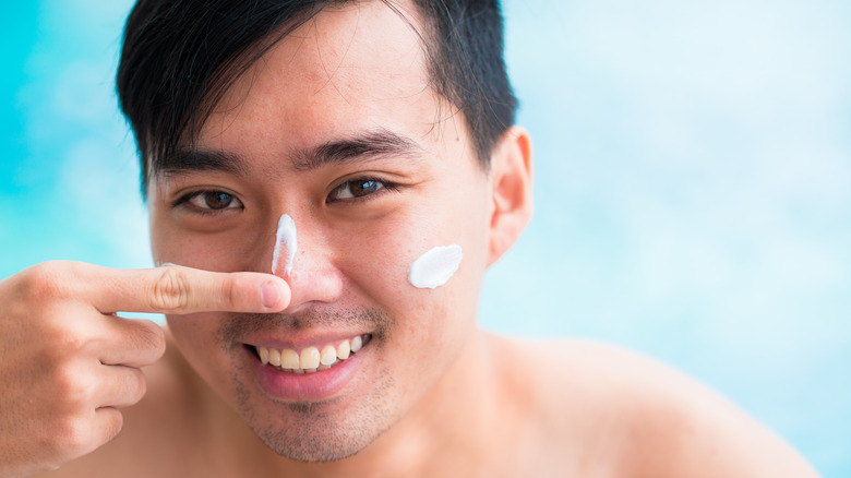 man applying sunscreen to face