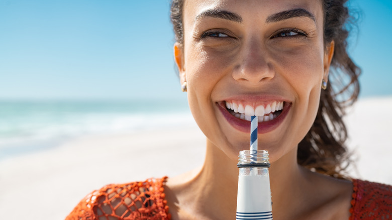 smiling woman drinking water from a straw