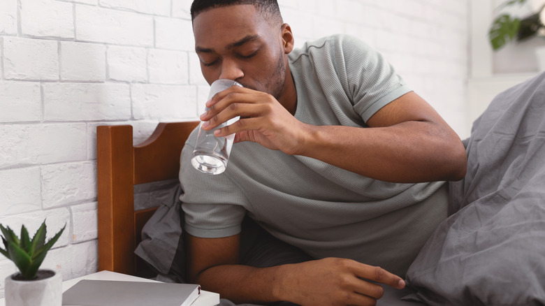 man drinking water in bed