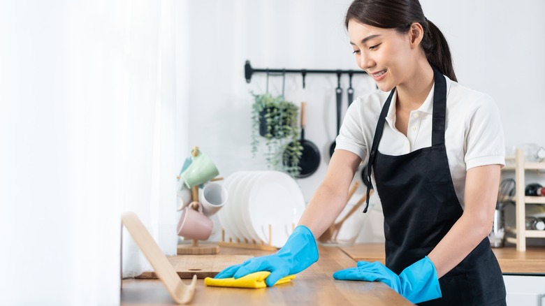 young woman cleaning kitchen table at home
