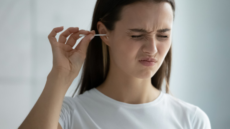 woman cleaning ear with cotton swab