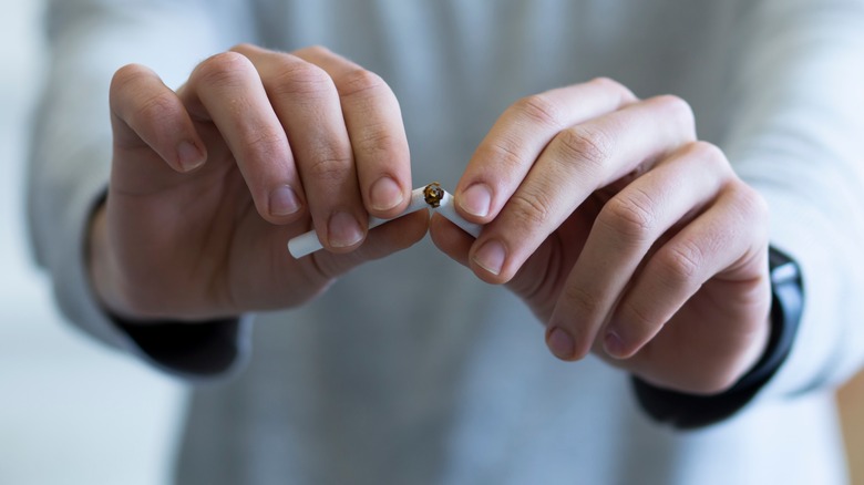 person snapping cigarette in half