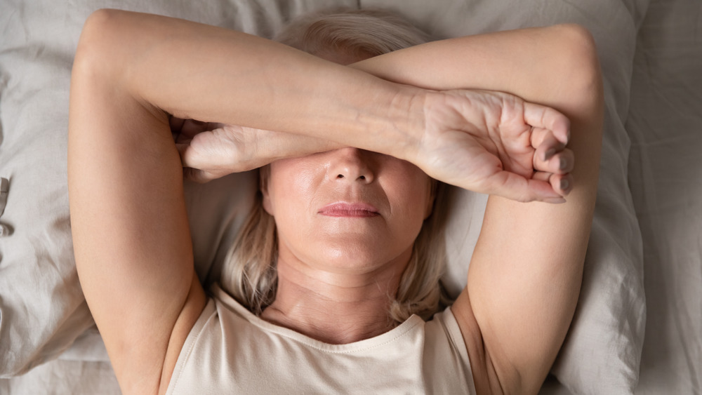 woman in bed covering eyes