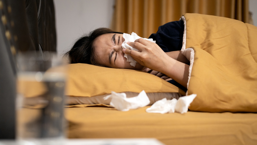 woman blowing nose in bed