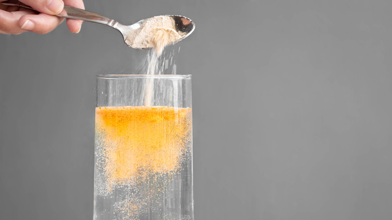 person pouring a powdered mix into water