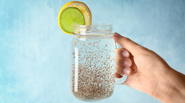 a woman holding a mason jar of chia seed water 