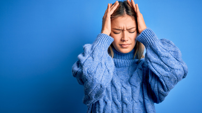 upset woman holding both hands to head