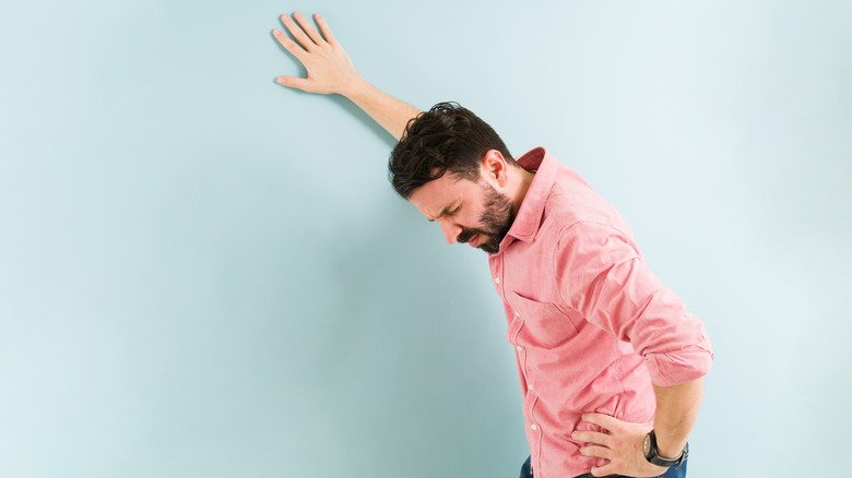 man with beard with one hand on wall