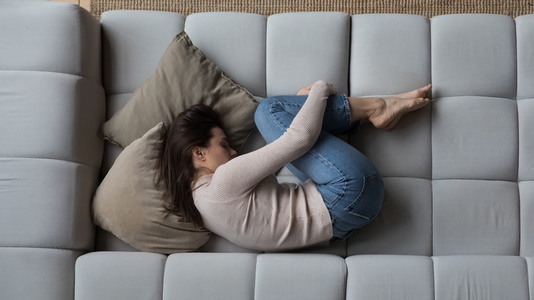 depressed woman curled up on couch