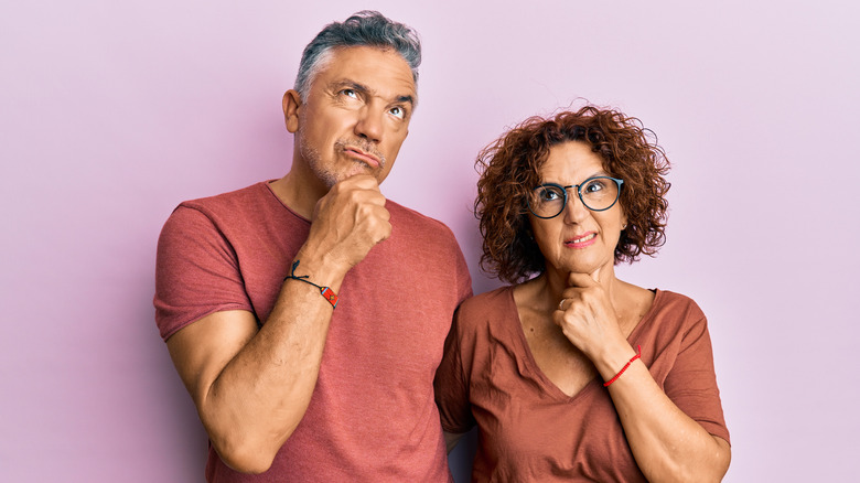 middle-aged confused man and woman with hands on chin