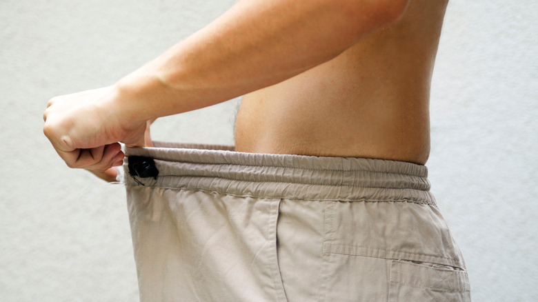 Man holding waistband of his pants to check penis