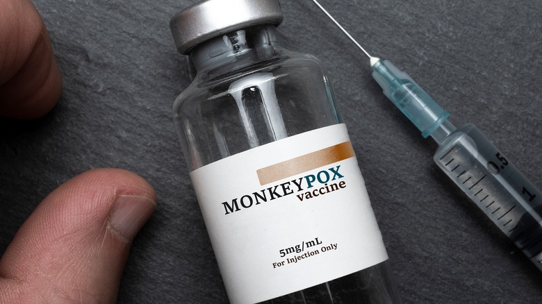 Monkeypox vaccine vial and syringe next to a hand