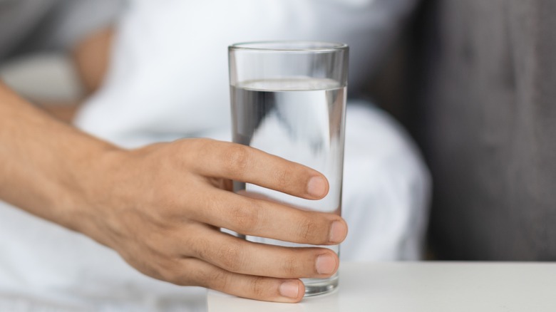 man reaching for glass of water