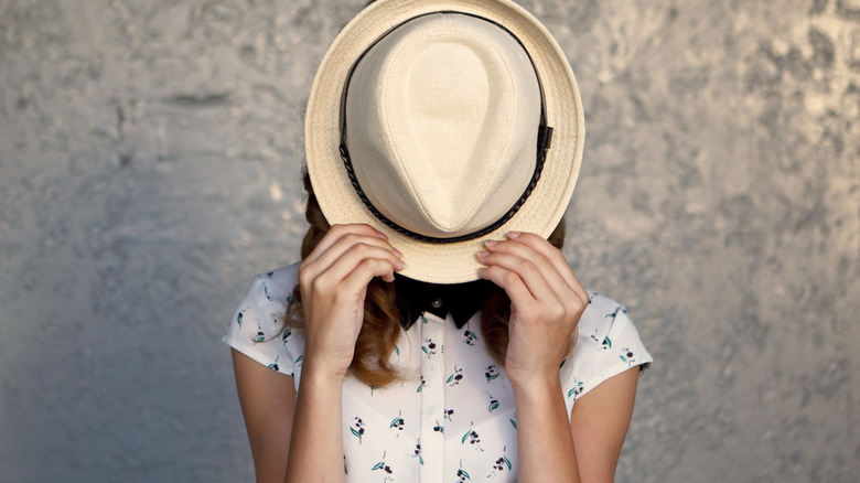 woman hiding behind hat