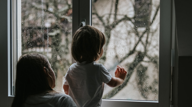 Little boy and girl looking at rain out window