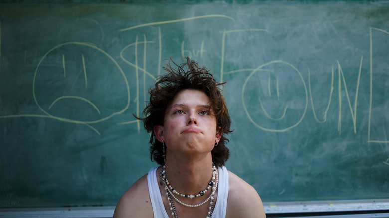 Jacob Sartorius sitting in front of a chalkboard making a funny face