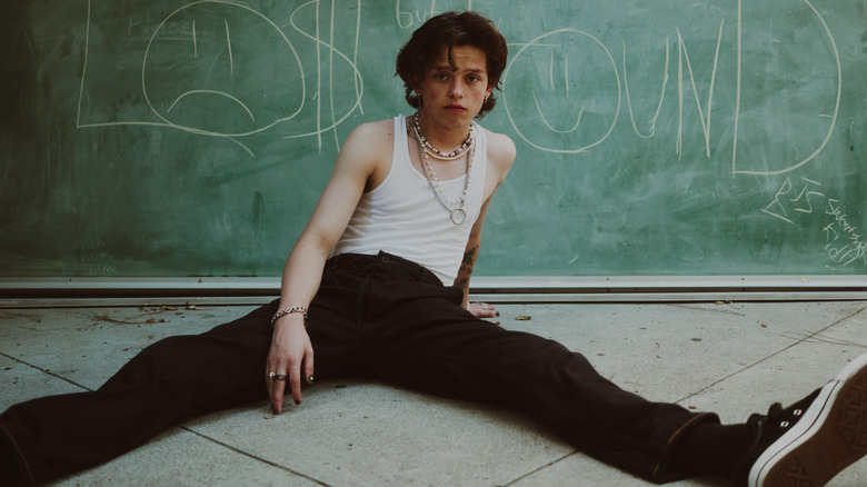Jacob Sartorius sitting in front of a chalkboard with the words 'Lost but Found' written on it